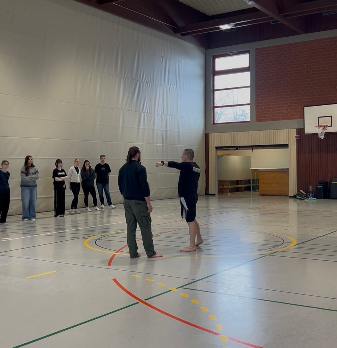Schülerinnen und Schüler erhalten Tipps von den erfahrenen Kampfkunst-Lehrern Andi und René für Prävention, Selbstbehauptung und Selbstverteidigung
